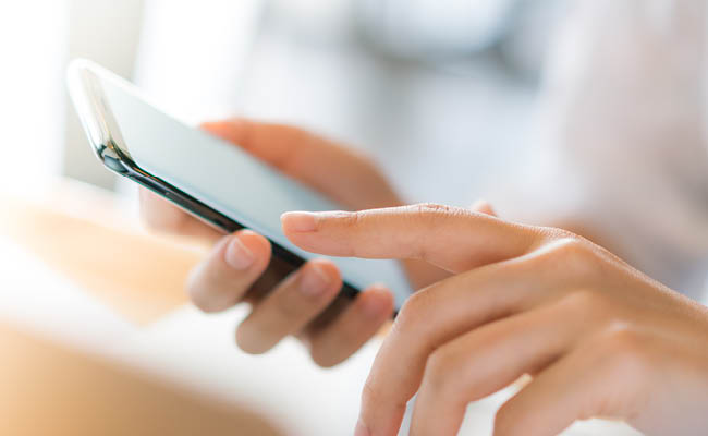 Close-up of hands holding and interacting with a smartphone.
