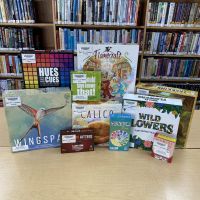 variety of board games displayed in front of a book shelf