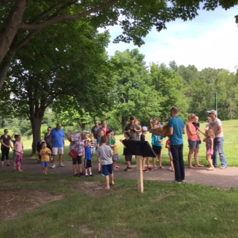 group of people gathered outside around storywalk frame