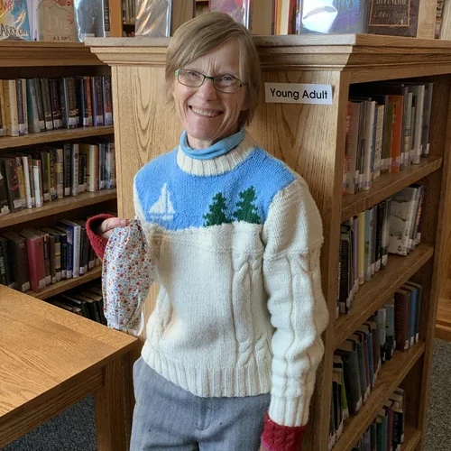 Laura Howe standing in front of a bookshelf at the library