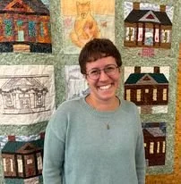 Annunziata Feldis standing in front of a quilt smiling