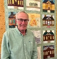 Bill Bland standing in front of a quilt smiling