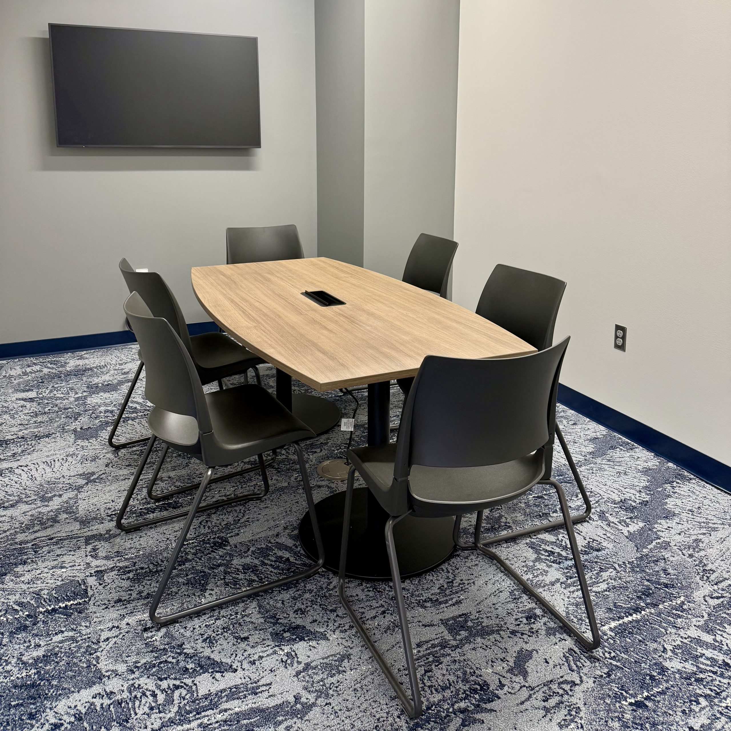 meeting room with six chairs, large table and tv screen