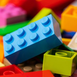 A pile of colorful Lego blocks, including blue, green, yellow, and orange, are scattered on a table.
